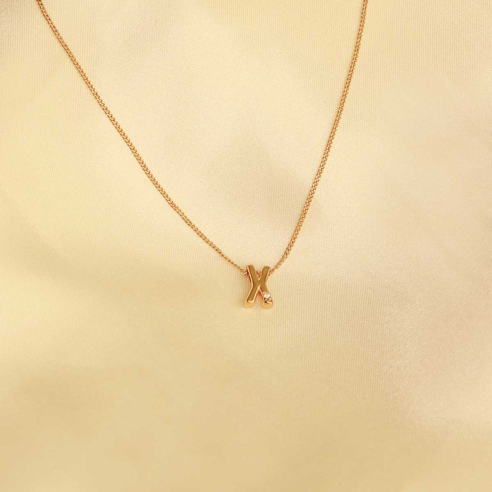 Flat lay shot of X Initial Pendant Necklace in Gold